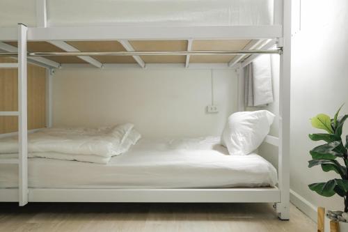 a white bunk bed with white sheets and pillows at The Roamery Hostel in Bangkok