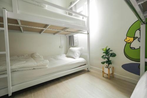 a bedroom with two bunk beds and a plant at The Roamery Hostel in Bangkok