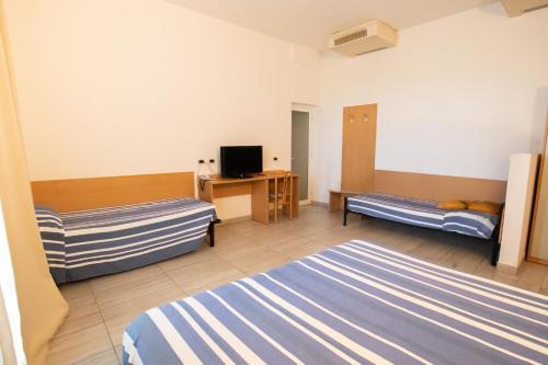a hotel room with two beds and a desk at Piccolo Hotel in Ravenna