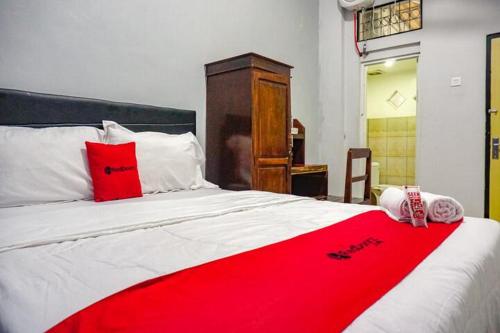 a bed with a red and white blanket on it at RedDoorz near Penimbangan Beach Singaraja in Singaraja