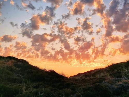 ブラーバンドにある8 person holiday home in Blåvandの丘の上の夕日の曇り空