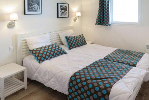 a bedroom with a white bed with blue pillows at Mimizan plage Balcon des pêcheurs in Mimizan-Plage