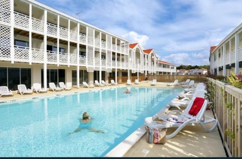 a hotel swimming pool with lounge chairs and people in it at Mimizan plage Balcon des pêcheurs in Mimizan-Plage