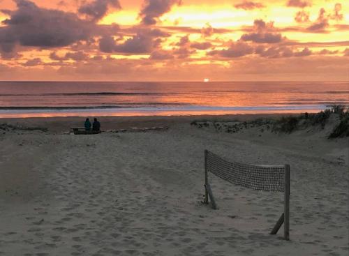 two people sitting on a beach with a volleyball net at Mimizan plage Balcon des pêcheurs in Mimizan-Plage