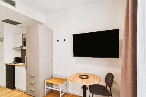 a living room with a table and a tv on a wall at Limehome Piraeus Iris in Piraeus