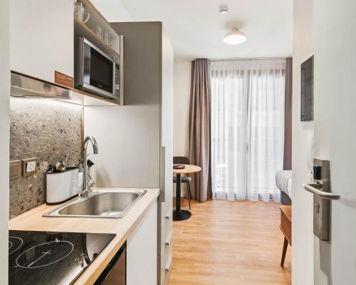 a small kitchen with a sink and a living room at Limehome Piraeus Iris in Piraeus