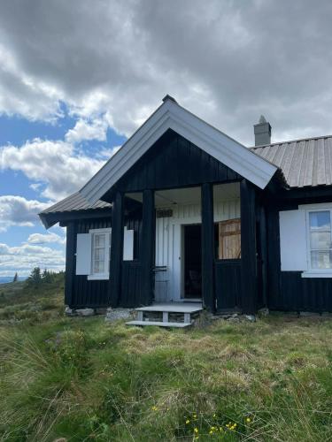 a black and white house in a field at Traditional Mountain Cabin Near Hallingskarvet in Torpo