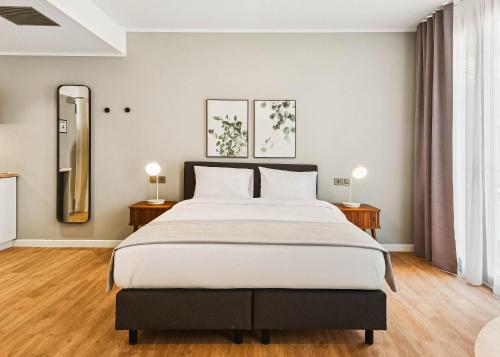 a bedroom with a large bed and two lamps at Limehome Piraeus Iris in Piraeus