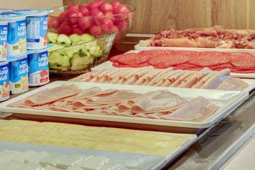 a table topped with trays of meat and other foods at B&B HOTEL Sado Setúbal in Setúbal