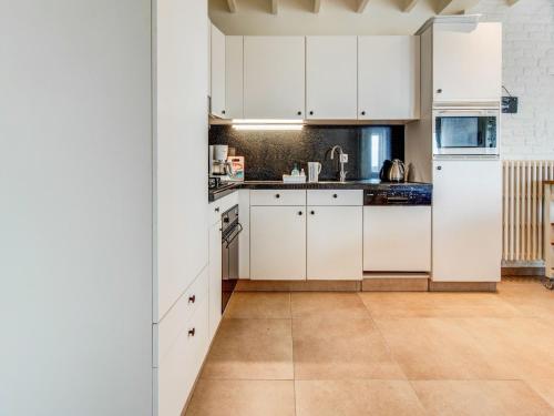 a kitchen with white cabinets and a tile floor at Holiday Home in Koekelare with Scenic Views in Koekelare