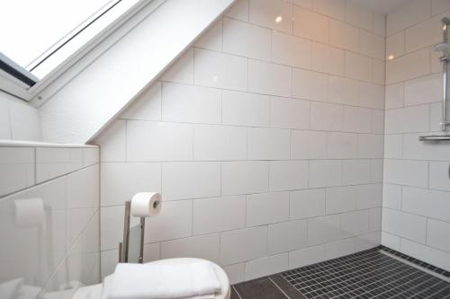 a bathroom with white tiled walls and a skylight at Deichhöhe 7 HO 1 in Norddeich