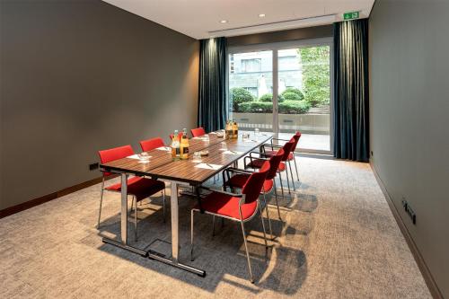 a conference room with a long table and red chairs at Radisson Blu Media Harbour Hotel, Düsseldorf in Düsseldorf