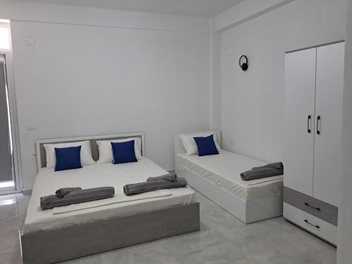 two beds in a white room with blue pillows at Apartments BIA in Gevgelija
