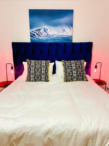 a bed with a blue headboard and two pillows at Stylish beachside Gem in Fish Hoek in Fish Hoek