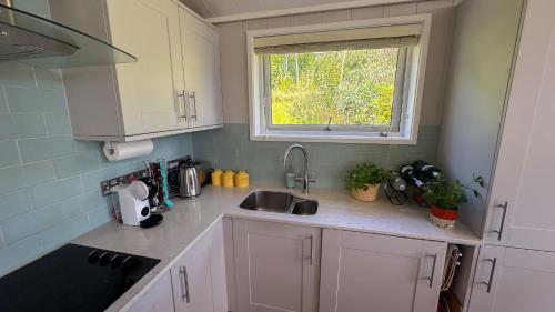 a kitchen with white cabinets and a sink and a window at Wye Knot - Modern Country Retreat with Views in Mathon