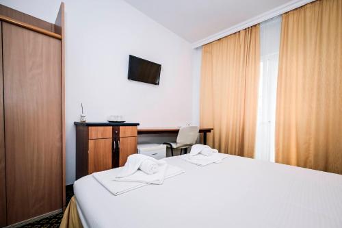 a hotel room with a white bed and a chair at Visconti Militari in Bucharest