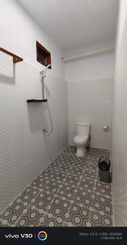 a bathroom with a toilet and a tile floor at Teman Homestay in Kuta Lombok