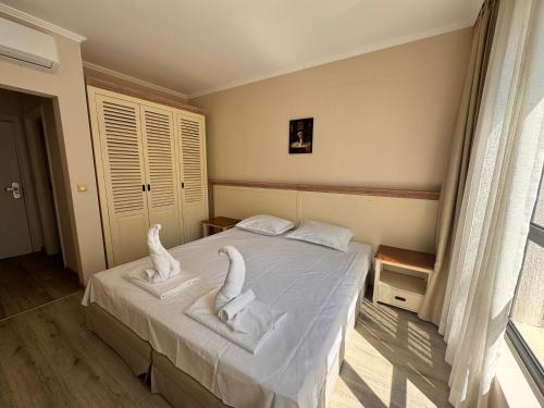 a bedroom with a bed with towel animals on it at White Rock Castle Apartments - Pool & SPA in Balchik