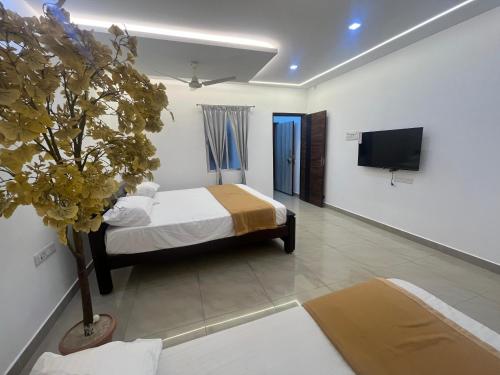 ein Schlafzimmer mit einem Bett und einem Fernseher an der Wand in der Unterkunft Sakthi Guest House in Tiruvannāmalai