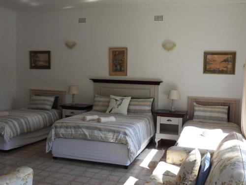 1 Schlafzimmer mit 2 Betten und 2 Stühlen in der Unterkunft Sandy's Place Graaff Reinet in Graaff-Reinet