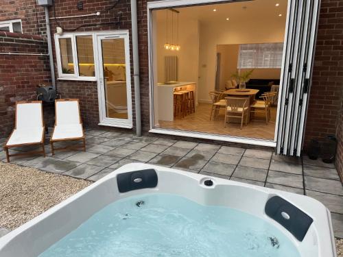 a bath tub sitting on a patio with a dining room at Seaglass No2 - Luxury 3 bed with optional hot tub in Seaham