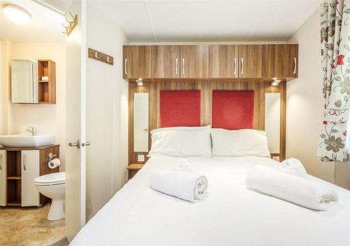 a bedroom with a white bed and a toilet at The Ness Hot tub Lodge in Fort Augustus