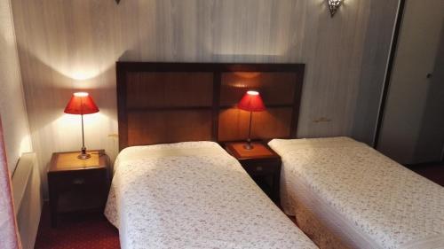two beds in a room with two lamps on tables at Le Ponant in Pradelles