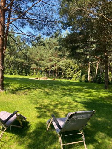 two lawn chairs sitting in the grass in a field at Dom Na Brzegu Ciszy in Pasym