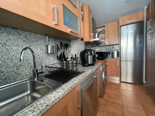 a kitchen with a sink and a stainless steel refrigerator at Cosy Apartment Resina Golf & Pool Estepona Costa del Sol in Estepona