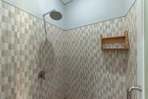 a bathroom with a shower with brown tiled walls at Urbanview Asung 2 Guesthouse near Canggu in Dalung
