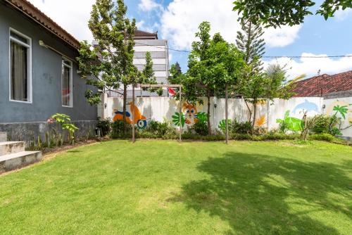 a backyard with a fence and a yard with green grass at Urbanview Asung 2 Guesthouse near Canggu in Dalung