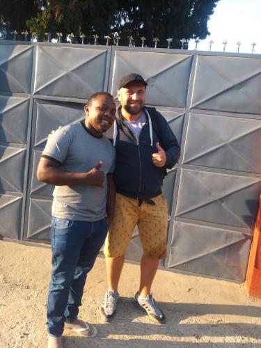 two men posing for a picture in front of a wall at Msovi House in Arusha