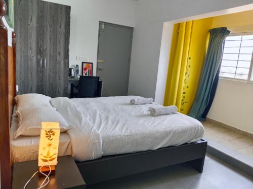 a bedroom with a large bed and a yellow curtain at Auro Maison in Puducherry