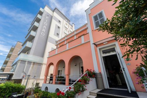 a pink building with flowers in front of it at Amadei Hotel Blumen in Pesaro