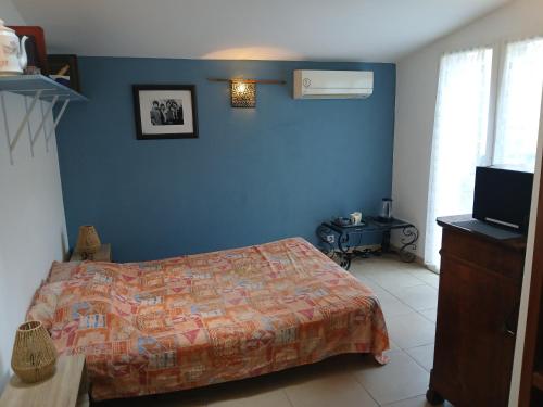 Un dormitorio con una cama y una pared azul. en Chambre avec SDB WC à 100 m du départ du GR20, en Calenzana