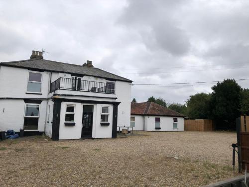 a white house with a balcony and a yard at Watton Vibe Hotel in Watton