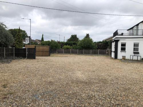 a large yard with a white house and a fence at Watton Vibe Hotel in Watton