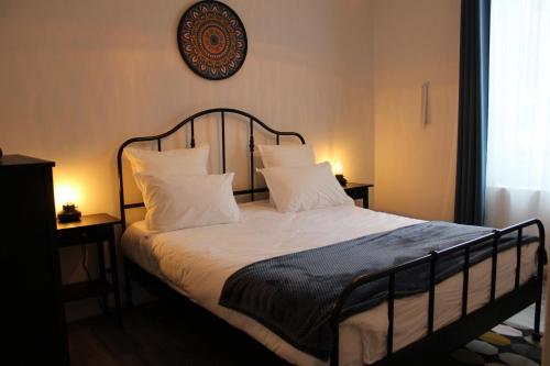 a bed with white pillows and a clock on the wall at Gîte Réole in Reignac