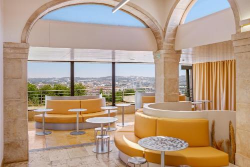 a lobby with yellow chairs and tables and a large window at B&B HOTEL Sado Setúbal in Setúbal