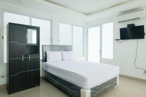 a bedroom with a bed and a cabinet and windows at David Houses Nusa Dua Beach Bali RedPartner in Nusa Dua