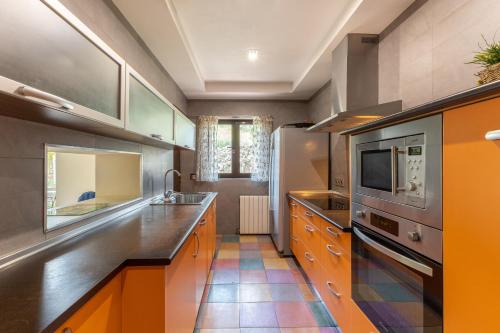 a large kitchen with orange cabinets and a microwave at El Herrén Del Abuelo in Vegas de Matute