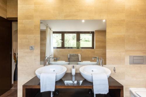 a bathroom with two sinks and a large mirror at El Herrén Del Abuelo in Vegas de Matute