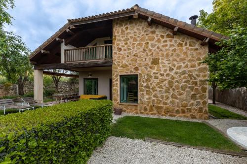 a stone house with a balcony and a patio at El Herrén Del Abuelo in Vegas de Matute
