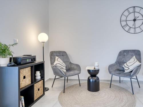 two chairs and a table in a living room with a clock at Villa Le Maris by Interhome in Dobrinj