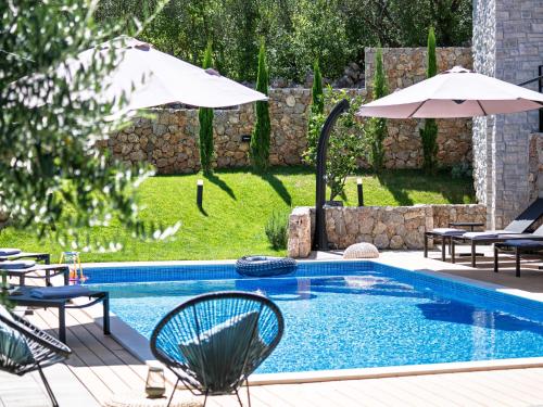 a pool with chairs and umbrellas in a yard at Villa Le Maris by Interhome in Dobrinj