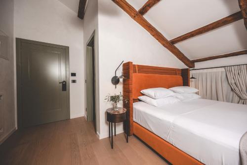 a bedroom with a bed with a wooden headboard and a door at Boutique Hotel San Rocco in Brtonigla