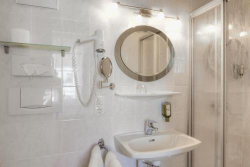 a white bathroom with a sink and a mirror at Hametner mit Innviertlerhaus mit Thermenzugang in Bad Hall