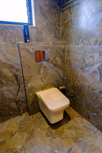 a bathroom with a toilet in a stone wall at Hotel Sterling Executive in Navi Mumbai