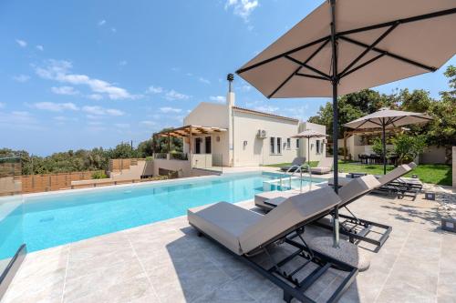 a pool with two lounge chairs and an umbrella at Athos Rural Villa in Prinés