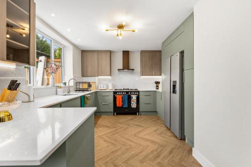 a kitchen with green cabinets and a wooden floor at Stylish group retreat with garden, games & parking in West London in Staines